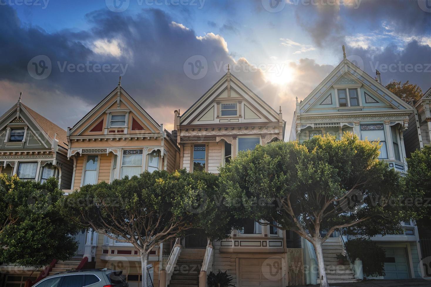 historische Häuser und Bäume im viktorianischen Stil unter bewölktem Himmel am Alamo Square foto