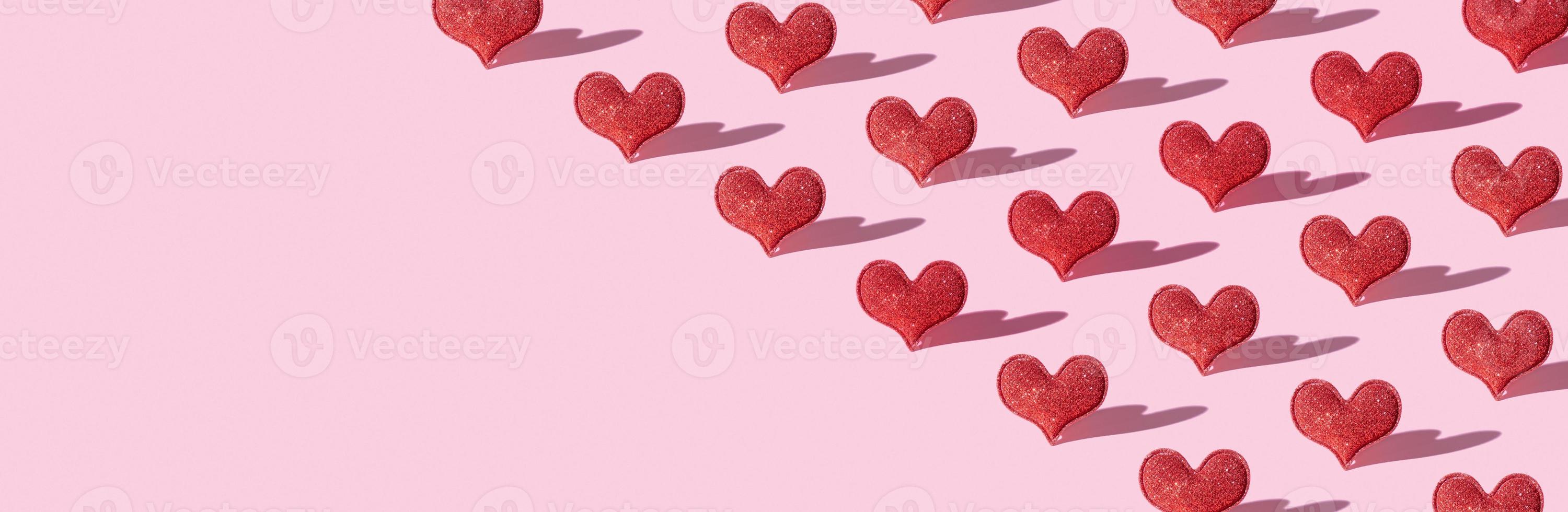 Muster mit roter Glitzerherzform auf rosa Hintergrund mit hartem Schatten. Valentinstag minimalistisches Symbol Liebe. Banner foto