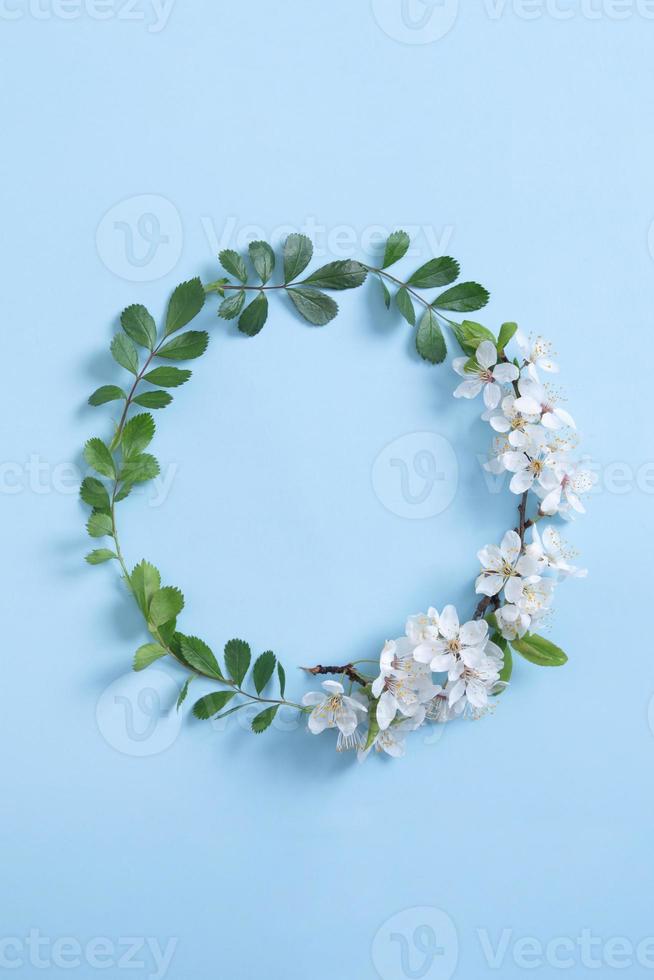 runder Wteath-Blumenrahmen für Ihren Frühlingstext. Blauer Hintergrund. Platz kopieren. vertikales Foto