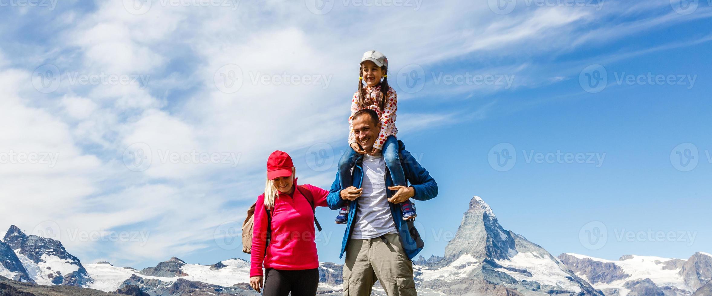 glückliche familie mit kleinem kind beim trekking auf dem schweizer berg im sommer. junge leute, die spaß in der landschaftsnatur haben. Reisekonzept, freundliche Familie foto