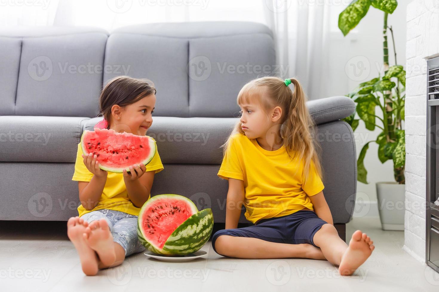 zwei Mädchen essen Wassermelone isoliert auf dem heimischen Hintergrund foto