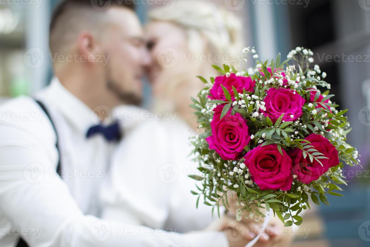 Hochzeitsstrauß auf dem Hintergrund eines verschwommenen küssenden Paares. Blumen und Liebhaber foto