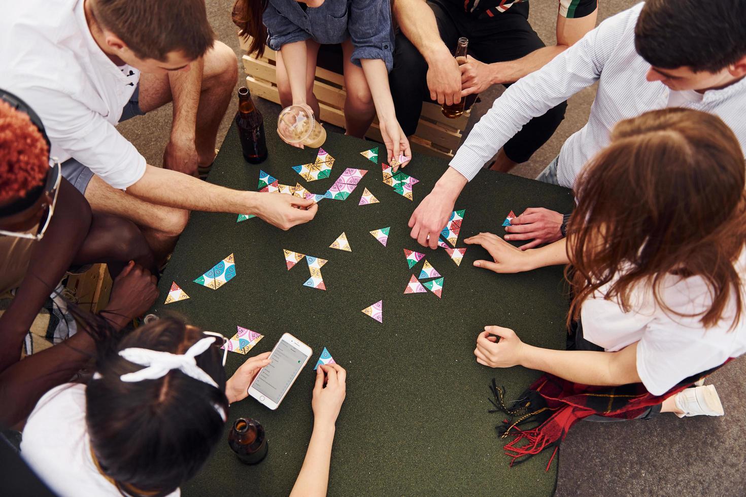 Kartenspiel spielen. eine gruppe junger leute in lässiger kleidung feiert tagsüber zusammen eine party auf dem dach foto