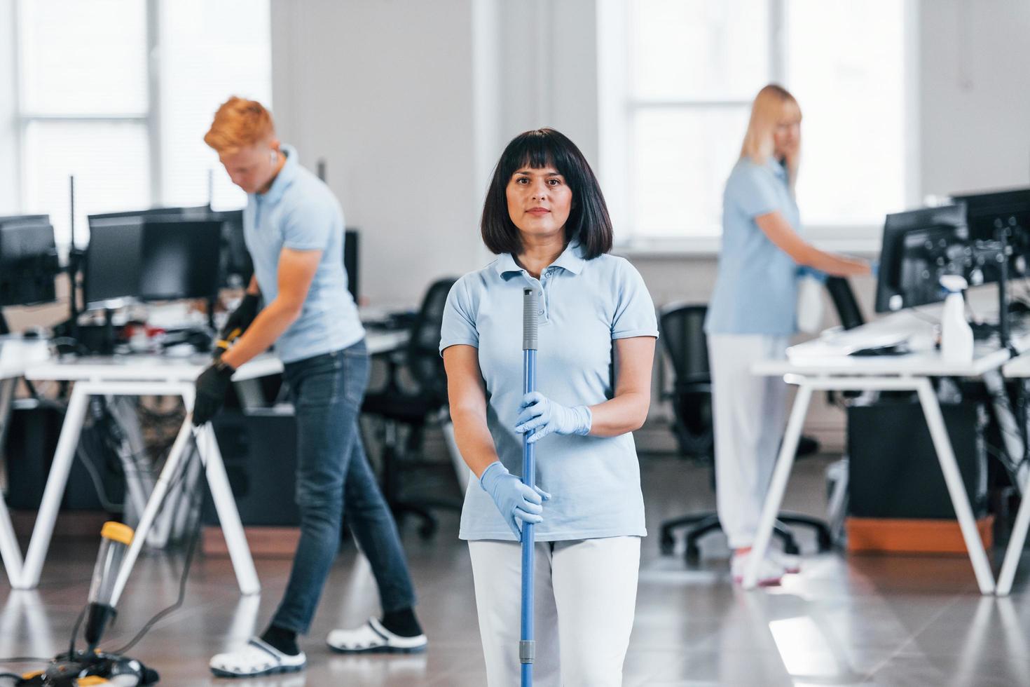 reinigt den Boden. gruppe von arbeitern reinigt tagsüber gemeinsam ein modernes büro foto