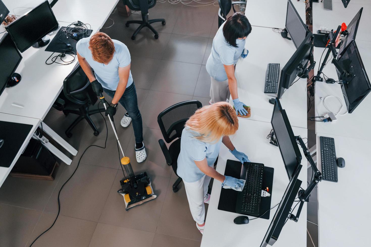 Ansicht von oben. gruppe von arbeitern reinigt tagsüber gemeinsam ein modernes büro foto