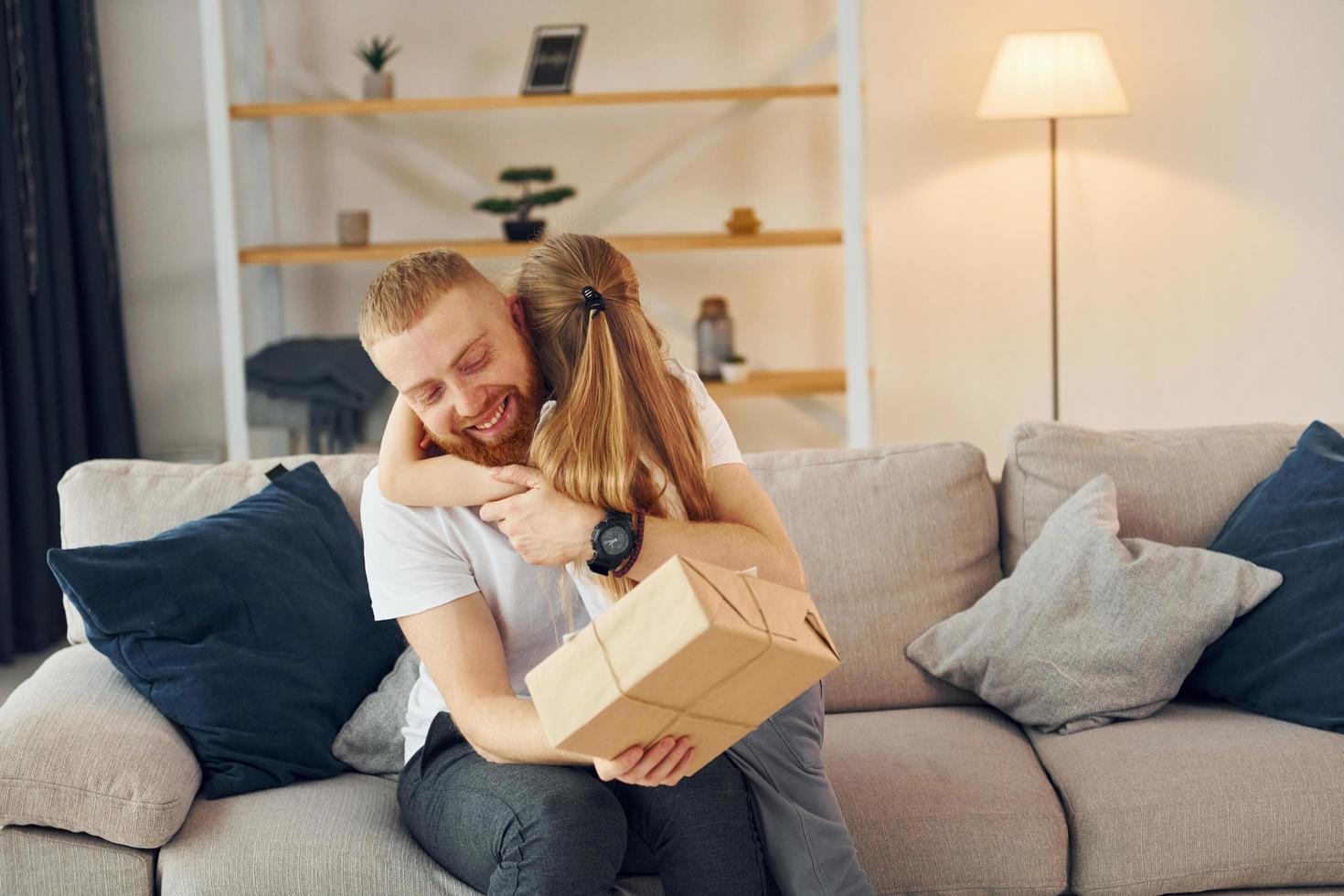 mit Geschenkbox. Vater mit seiner kleinen Tochter ist zusammen zu Hause foto