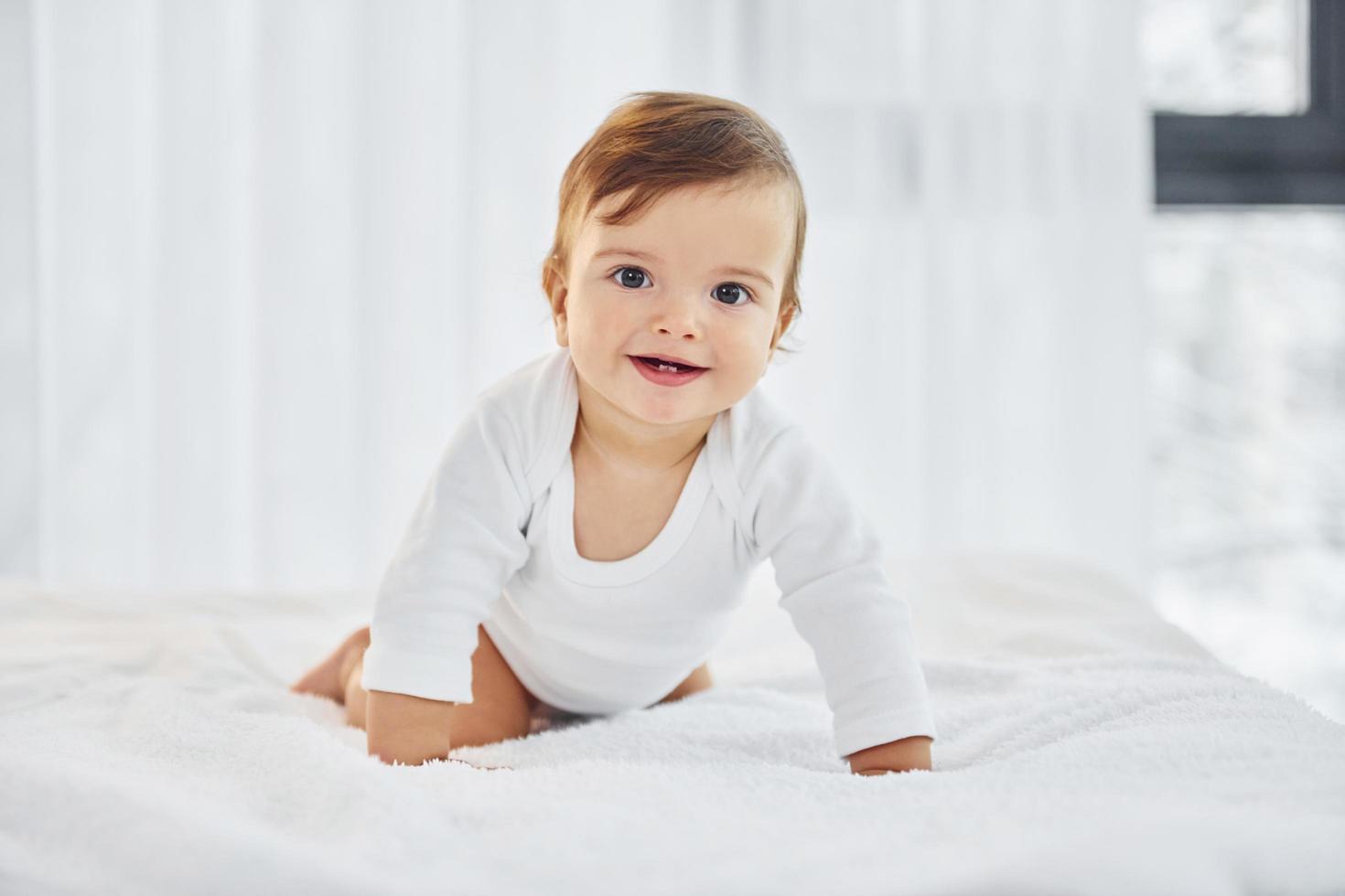 auf dem Bett spielen. süßes kleines baby ist drinnen im wohnzimmer foto