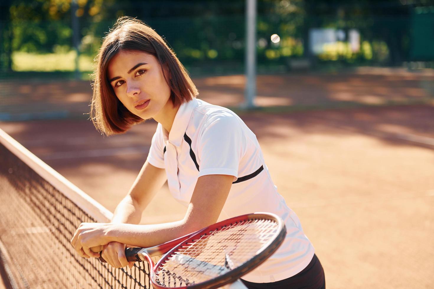 stehend mit Schläger in der Hand. Tennisspielerin ist tagsüber auf dem Platz foto