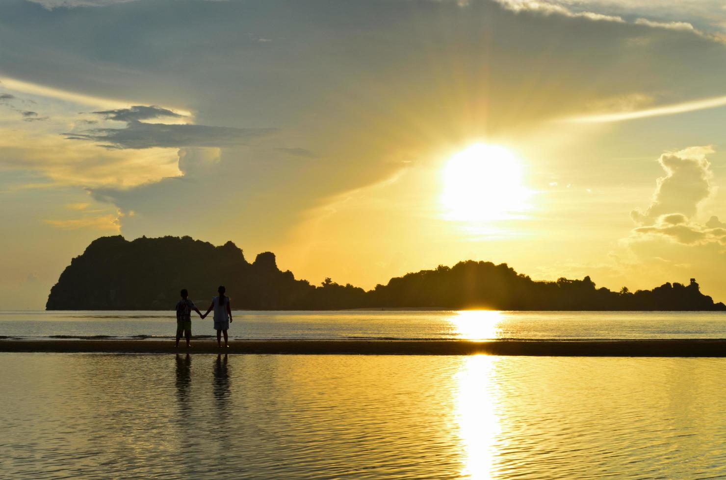 Zwei Kinder stehen am Strand und beobachten den Sonnenaufgang foto