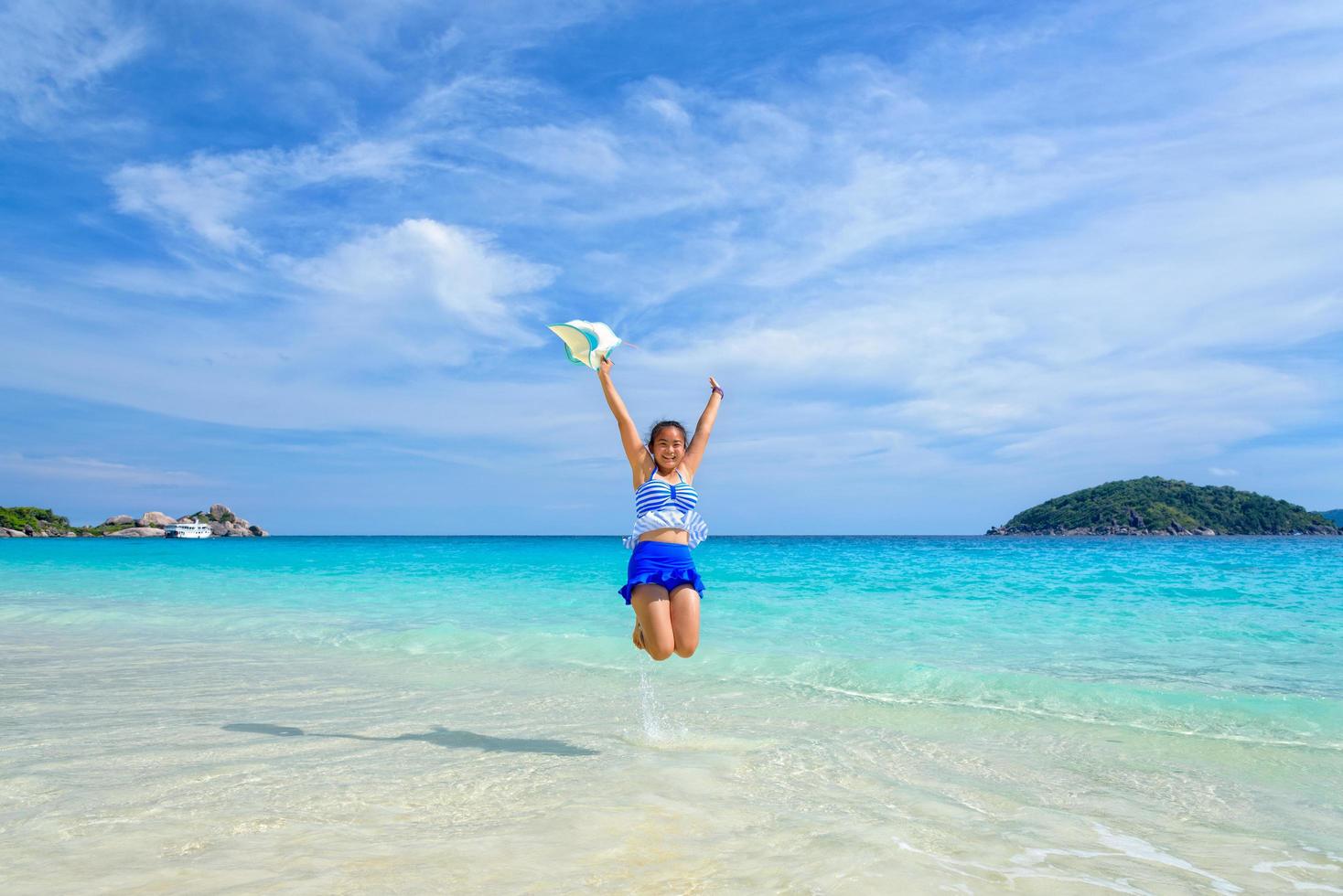 mädchen, das mit glücklichem auf dem strand in thailand springt foto