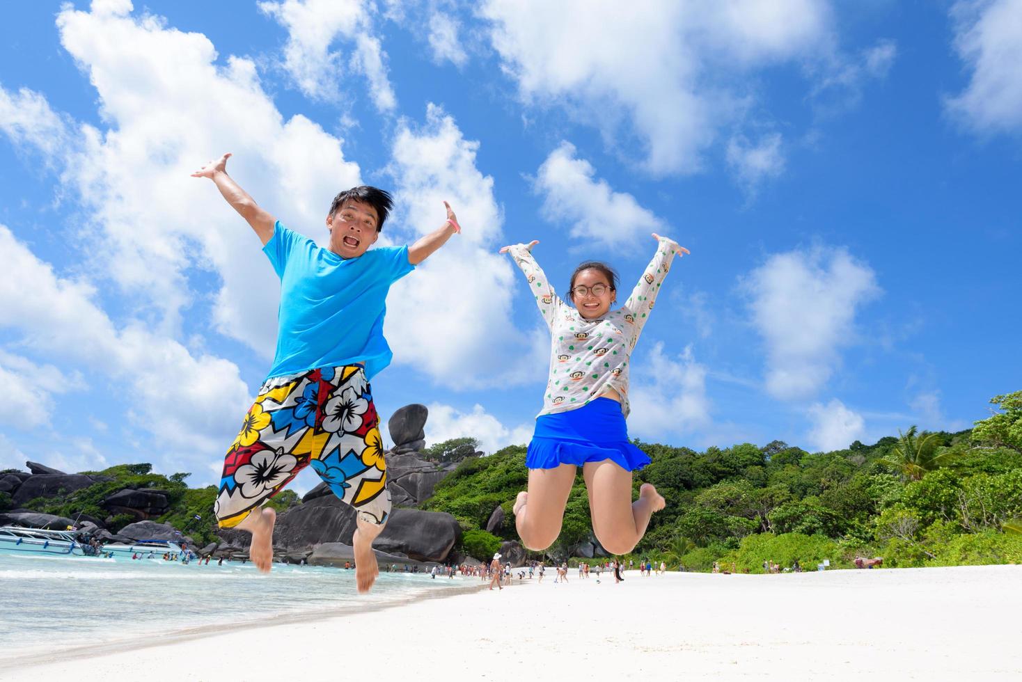 Vater und Tochter springen am Strand von Thailand foto