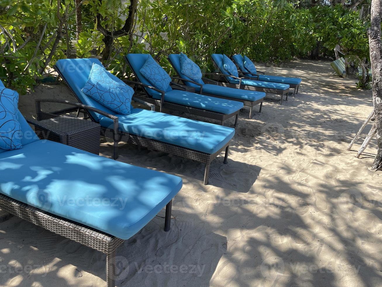 Liegestühle oder Liegestühle am weißen Sandstrand an heißen Sommertagen im tropischen Luxushotel foto