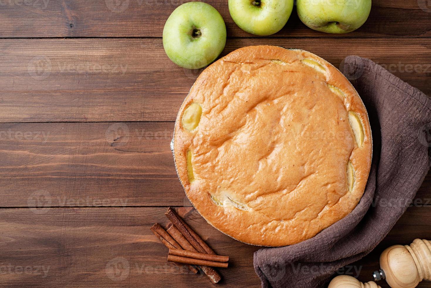 Apfelkuchen Charlotte auf Holztisch mit frischem Apfel und Zimt, Ansicht von oben foto