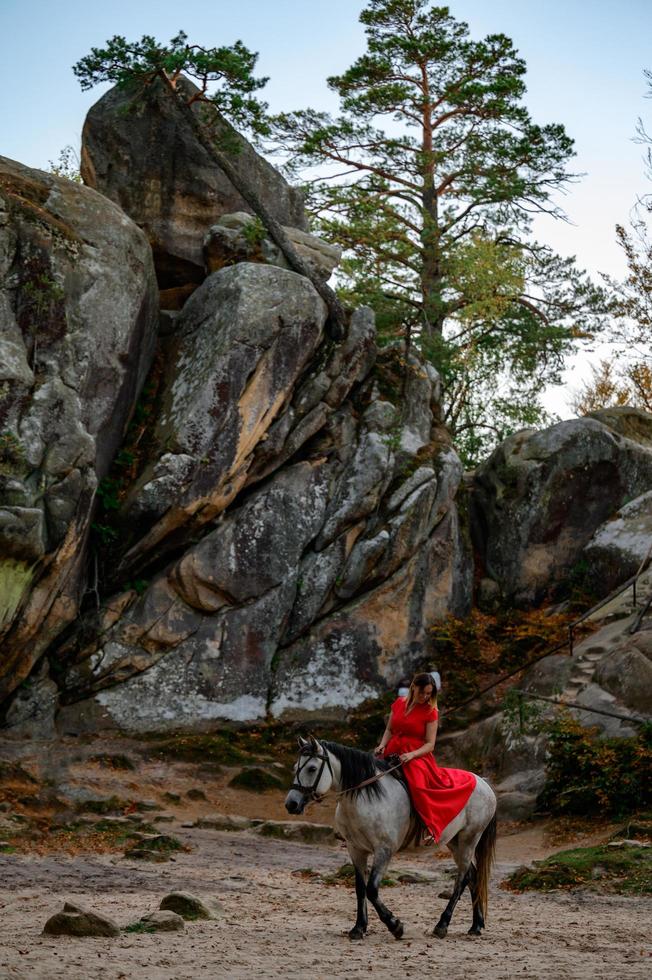 Dovbush-Felsen und Reiten, eine Frau, die in einem roten Kleid mit bloßen Füßen auf einem Pferd reitet. foto