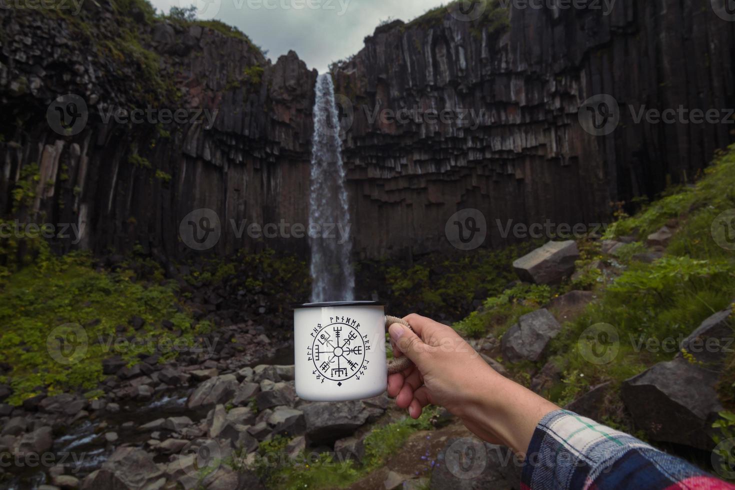 Nahaufnahme der männlichen Hand, die die Tassenfüllung in der Nähe des Wasserfall-Konzeptfotos imitiert foto