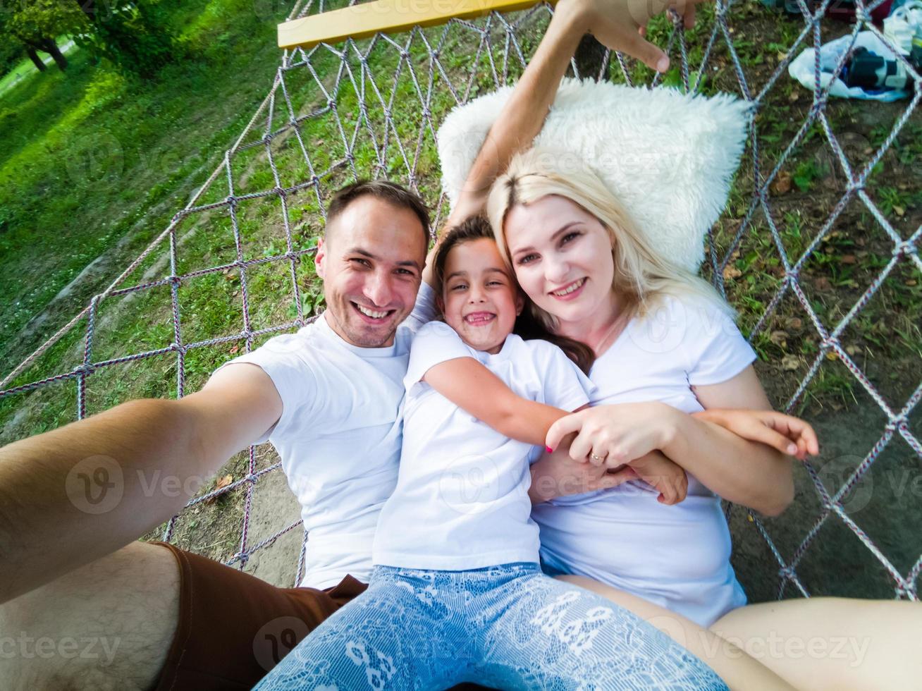 Familie, die sich an einem sonnigen Sommertag im Garten des Ferienhauses auf einer Hängematte niederlegt und entspannt. familie entspannen im freien, gesunder und wellness-lebensstil. foto