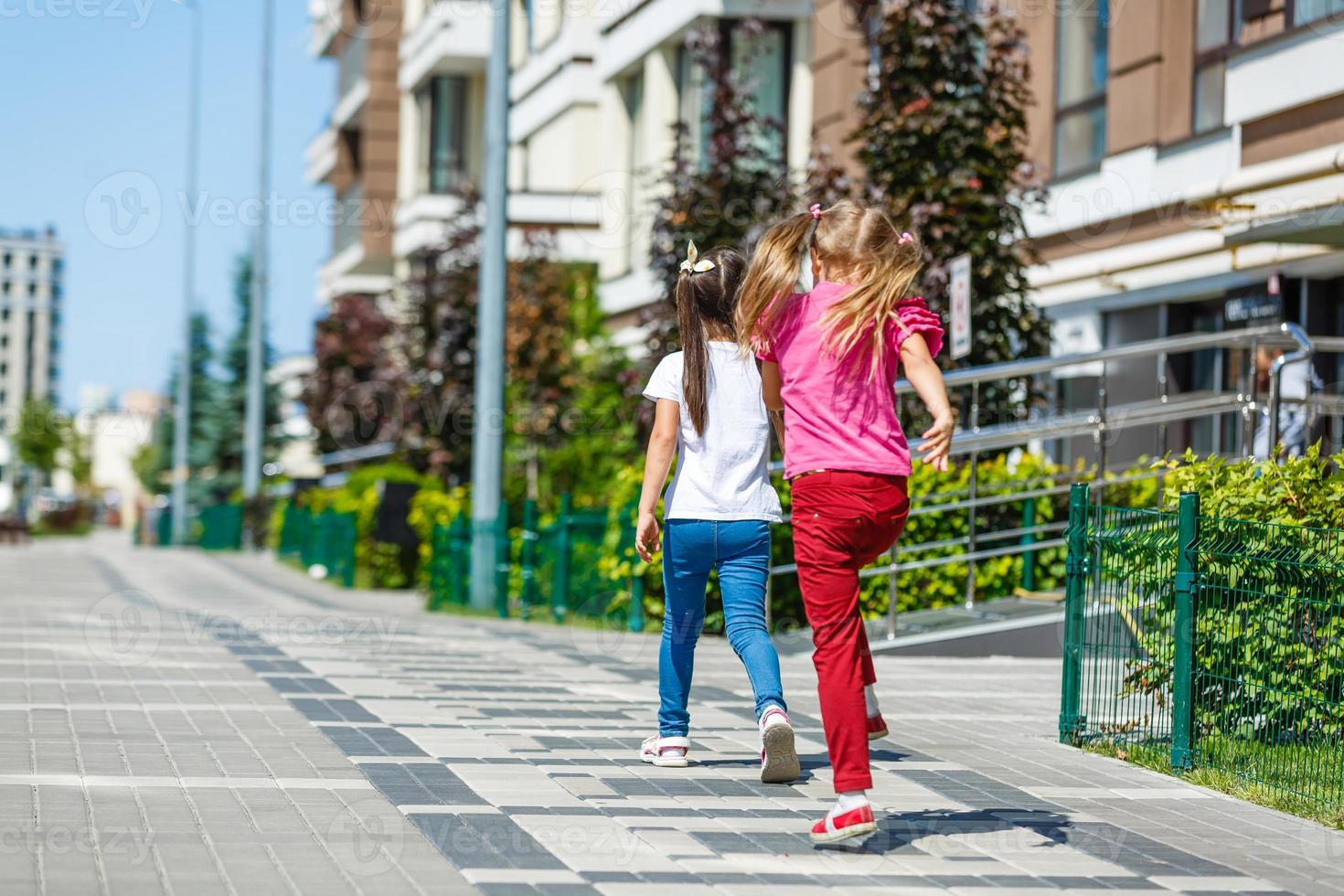 Zwei Schulmädchen mit Rucksack außerhalb der Grundschule. schulmädchen, grundschülerin, die von der schule geht, abschlussfeier, sommerferien. foto