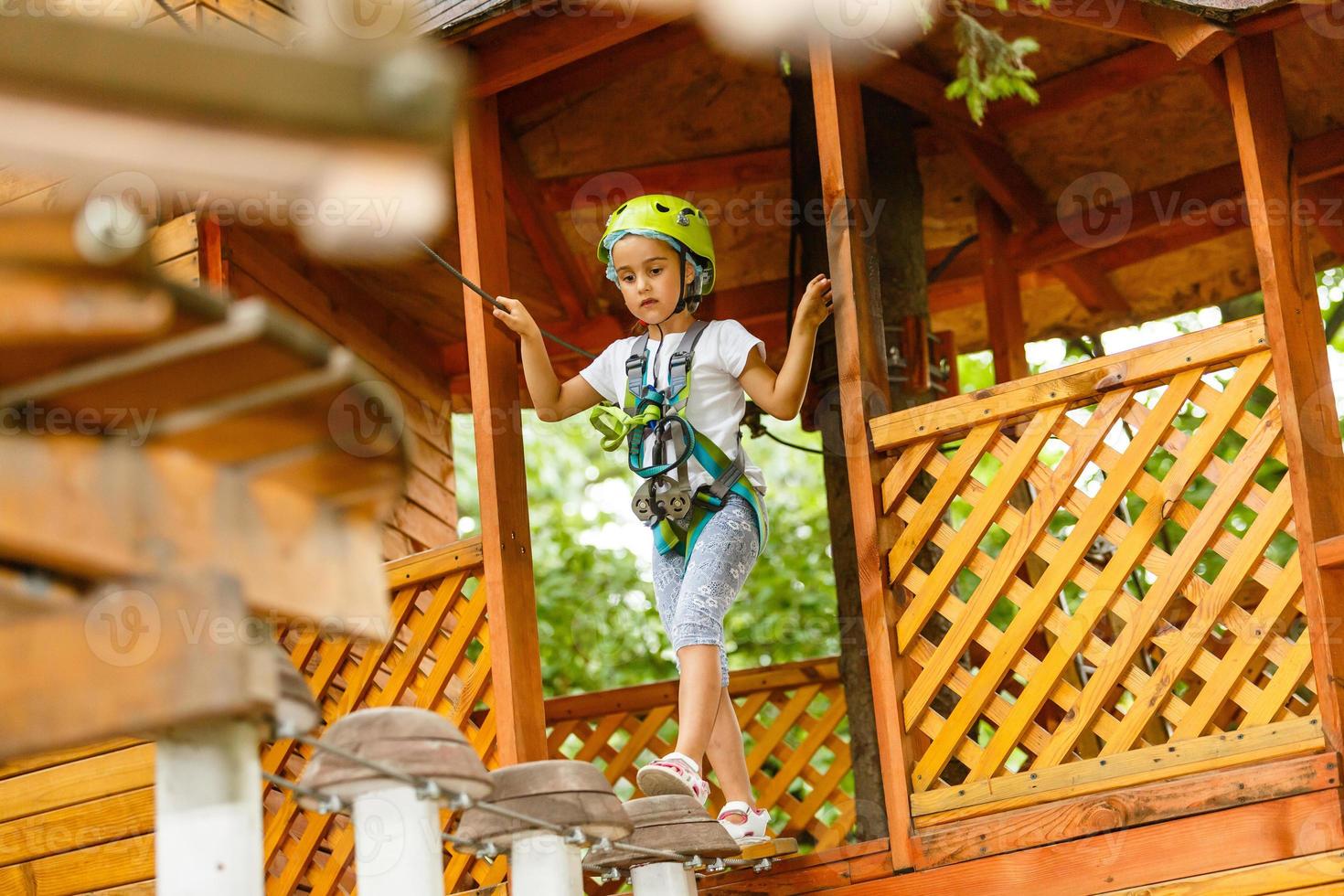 glückliches Schulmädchen, das Aktivität in einem Kletterabenteuerpark an einem Sommertag genießt foto