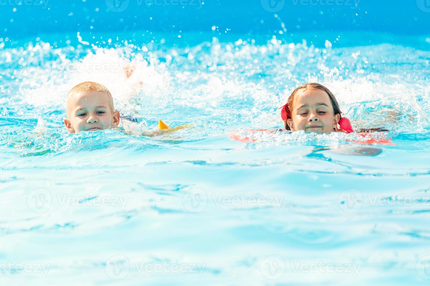 lächelnder Junge und kleines Mädchen schwimmen im Pool im Aquapark foto