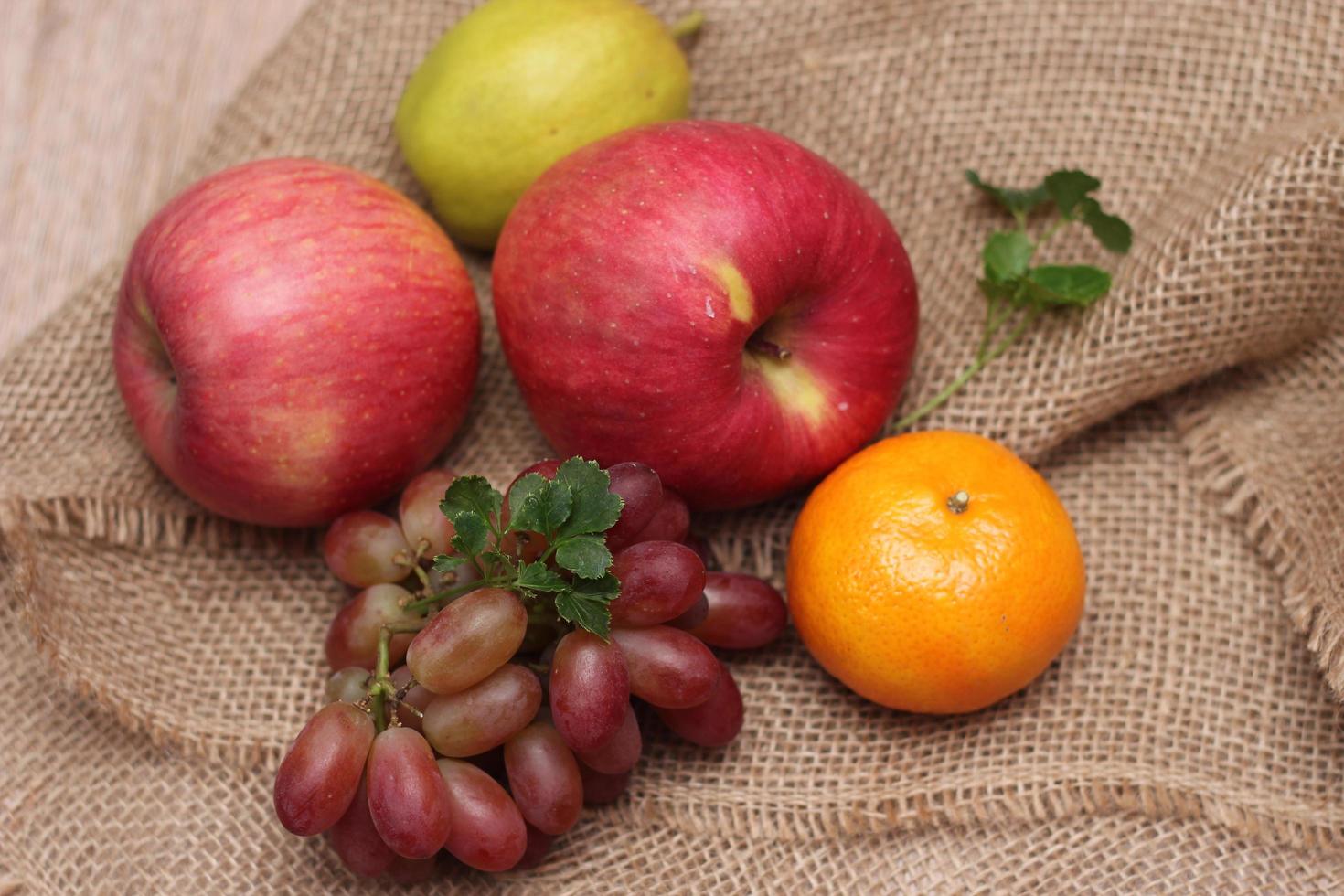 Früchte mit Vitamin C, die für den Körper von Vorteil sind. auf Sackleinen legen - Orange, Traube, Apfel, Guave foto