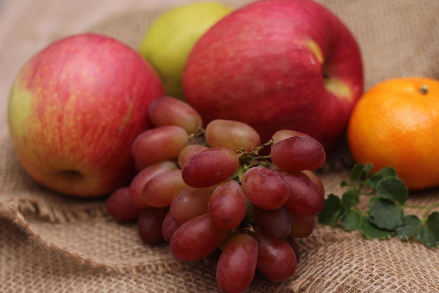 Früchte mit Vitamin C, die für den Körper von Vorteil sind. auf Sackleinen legen - Orange, Traube, Apfel, Guave foto