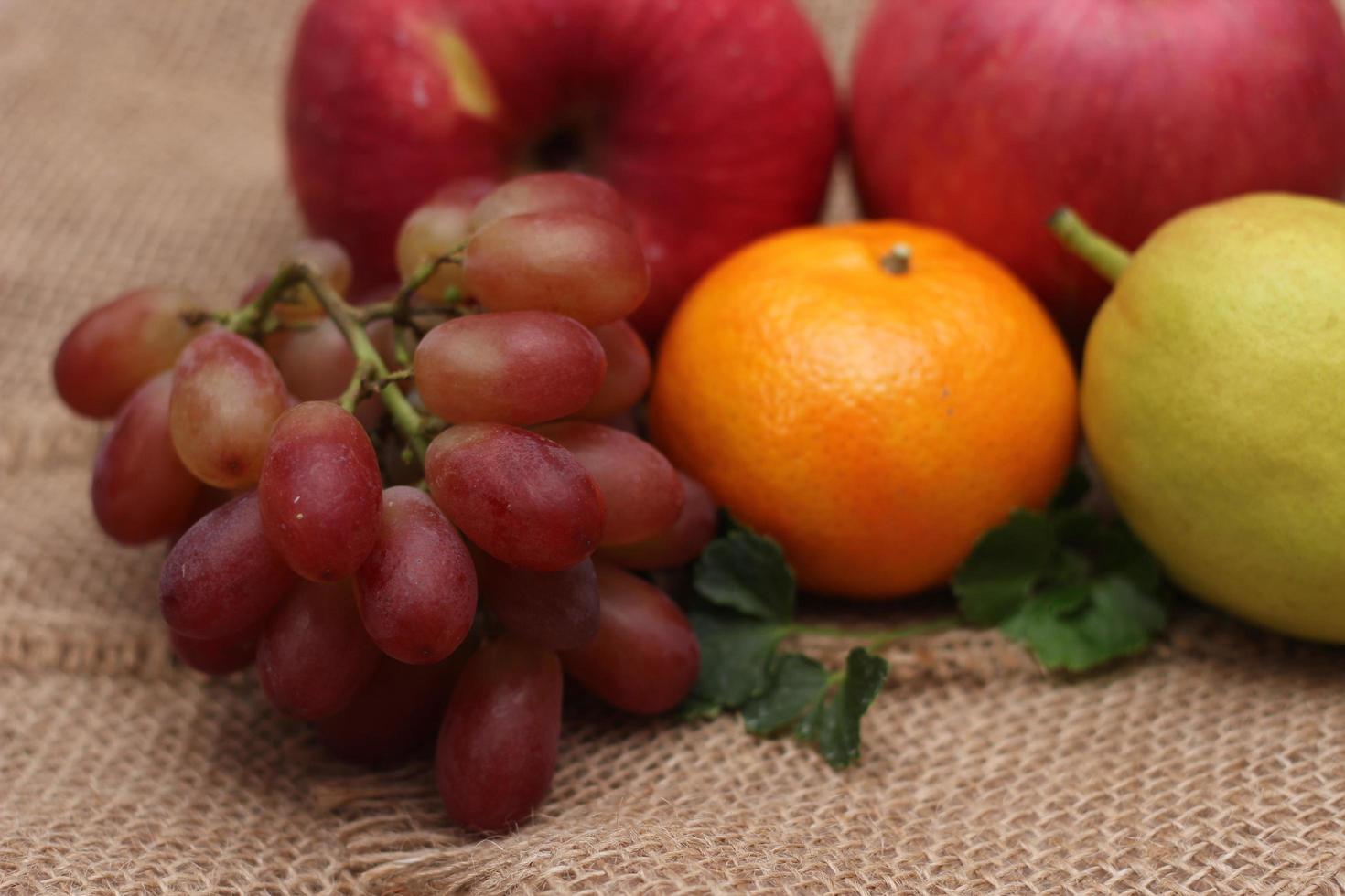 Früchte mit Vitamin C, die für den Körper von Vorteil sind. auf Sackleinen legen - Orange, Traube, Apfel, Guave foto