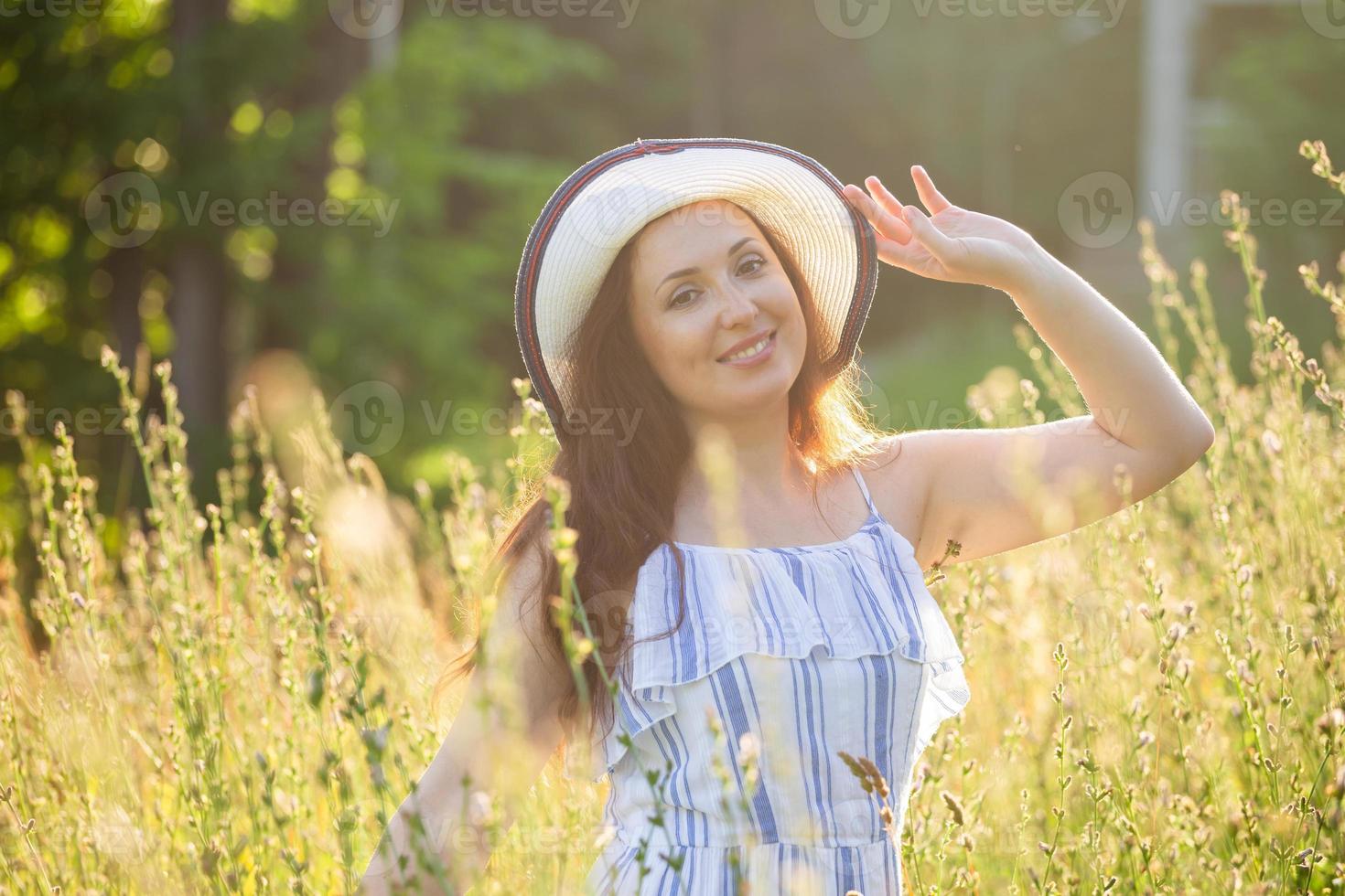 junge Frau, die an einem sonnigen Sommertag zwischen Wildblumen spazieren geht. Konzept der Freude an der Kommunikation mit der Sommernatur foto