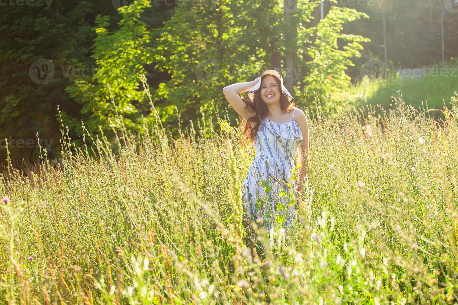 Frau, die an einem sonnigen Sommertag auf einem Feld spazieren geht. foto