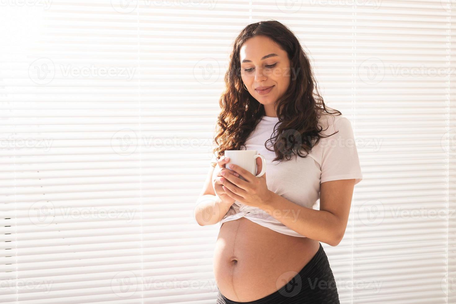 Glückliche schwangere junge schöne Frau trinkt Tee während des morgendlichen Frühstücks. Schwangerschaft und Mutterschutz. Platz kopieren. foto