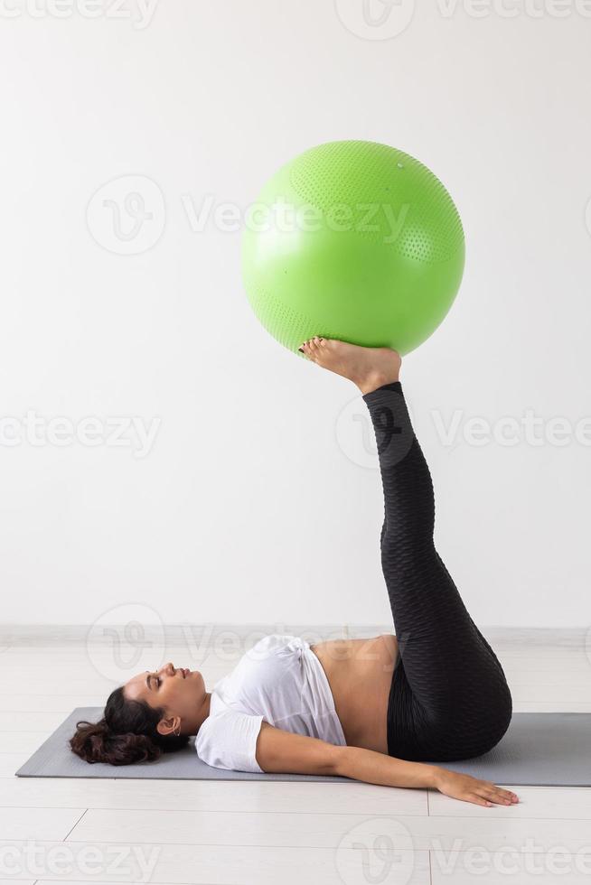 junge flexible schwangere Frau beim Turnen auf Teppich auf dem Boden auf weißem Hintergrund. das Konzept, den Körper auf eine leichte Geburt vorzubereiten foto