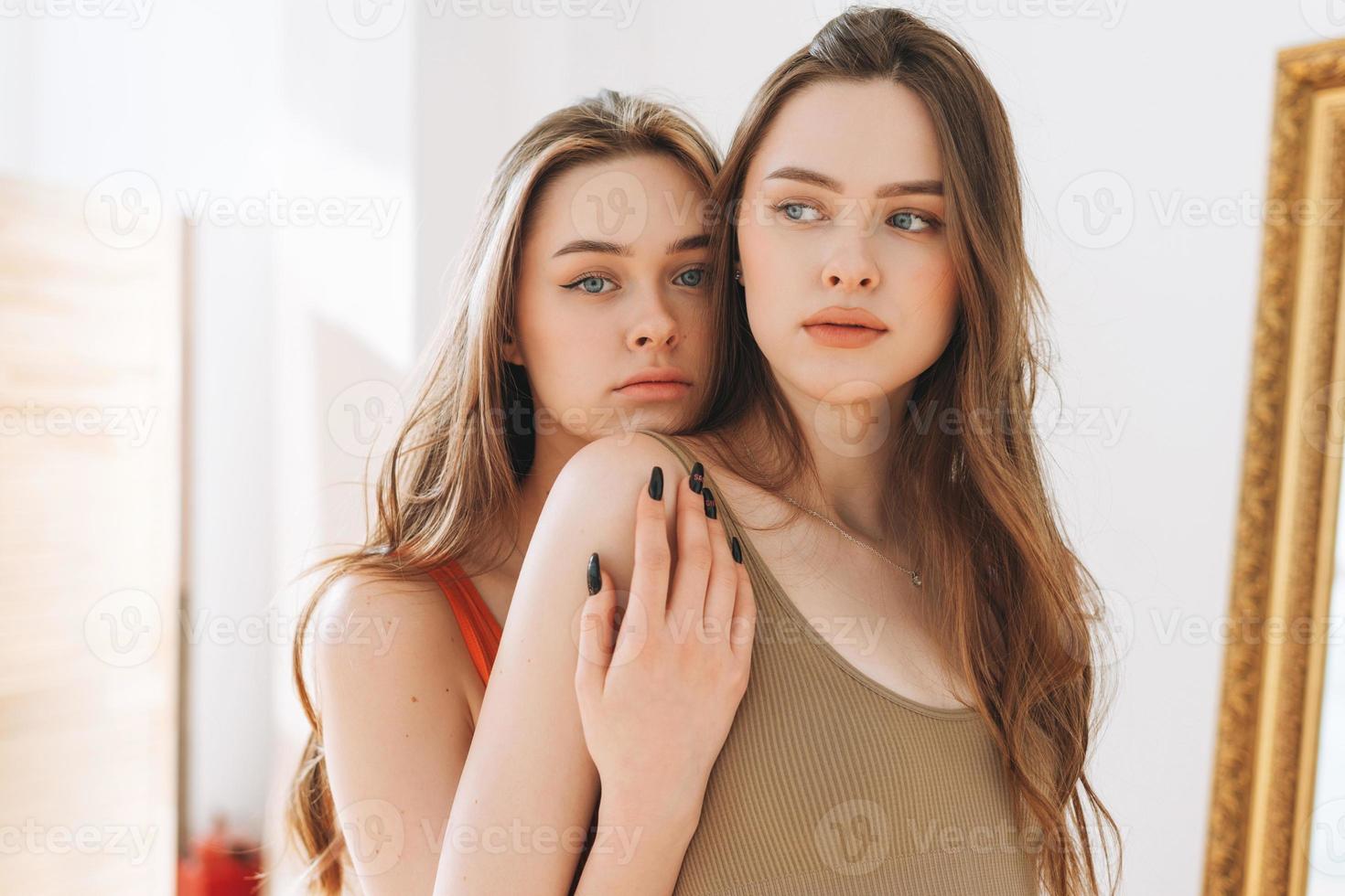 Fashion Beauty Models zwei Schwestern Zwillinge schöne Mädchen mit langen Haaren, die im hellen Studio in die Kamera schauen foto