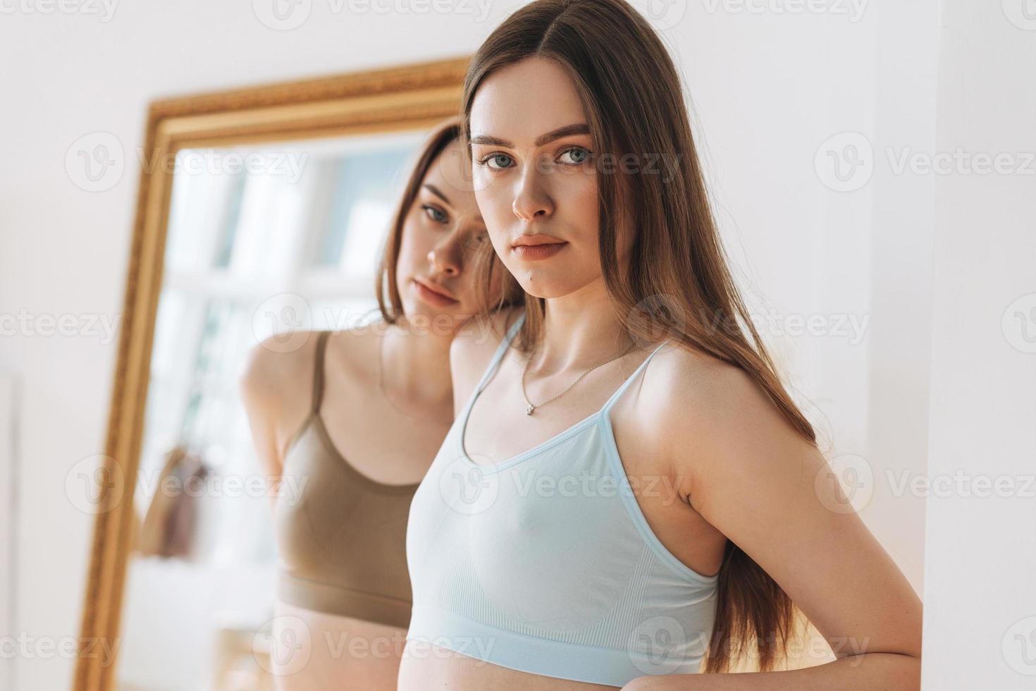 Fashion Beauty Models zwei Schwestern Zwillinge schöne Mädchen mit langen Haaren in sportlicher nahtloser gerippter Unterwäsche im hellen Studio foto