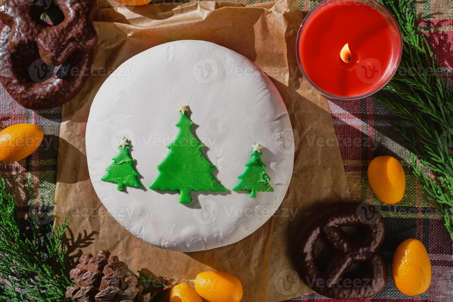 Stillleben mit weihnachtlichem Essen mit fruchtigem englischen Kuchen, verziert mit Tannenbäumen, bedeckt mit Marzipan. traditioneller weihnachtskuchen oder pudding, auf dem hintergrund von weihnachtsdekorationen, draufsicht foto