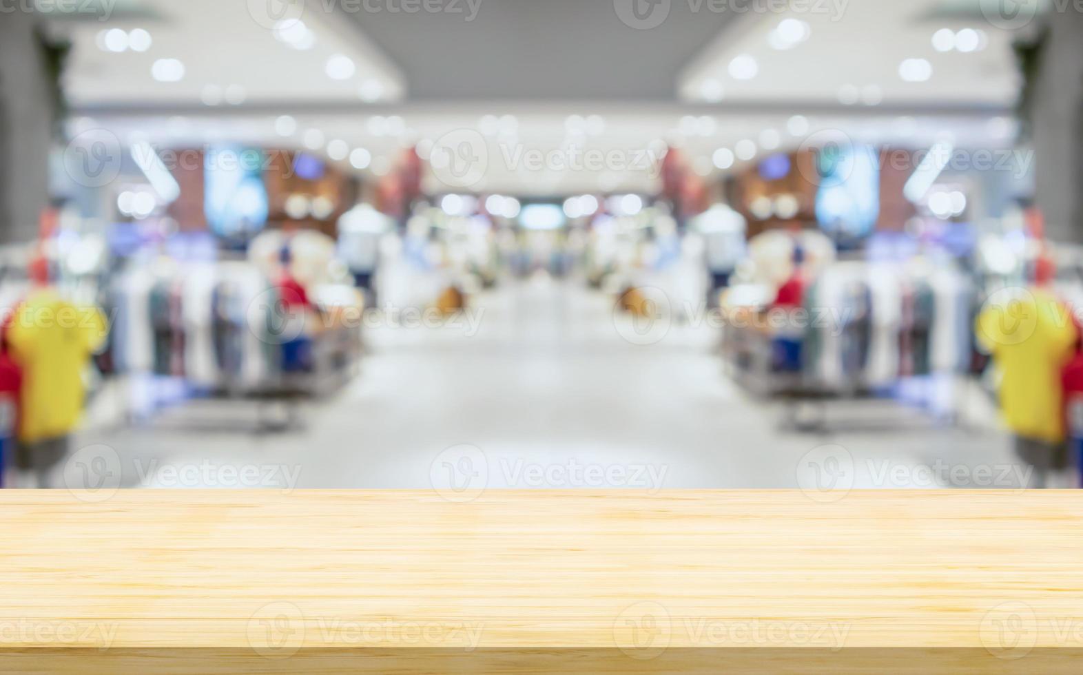 leere Holztischplatte mit verschwommener Bekleidungsboutique im Inneren des Einkaufszentrums Hintergrund foto