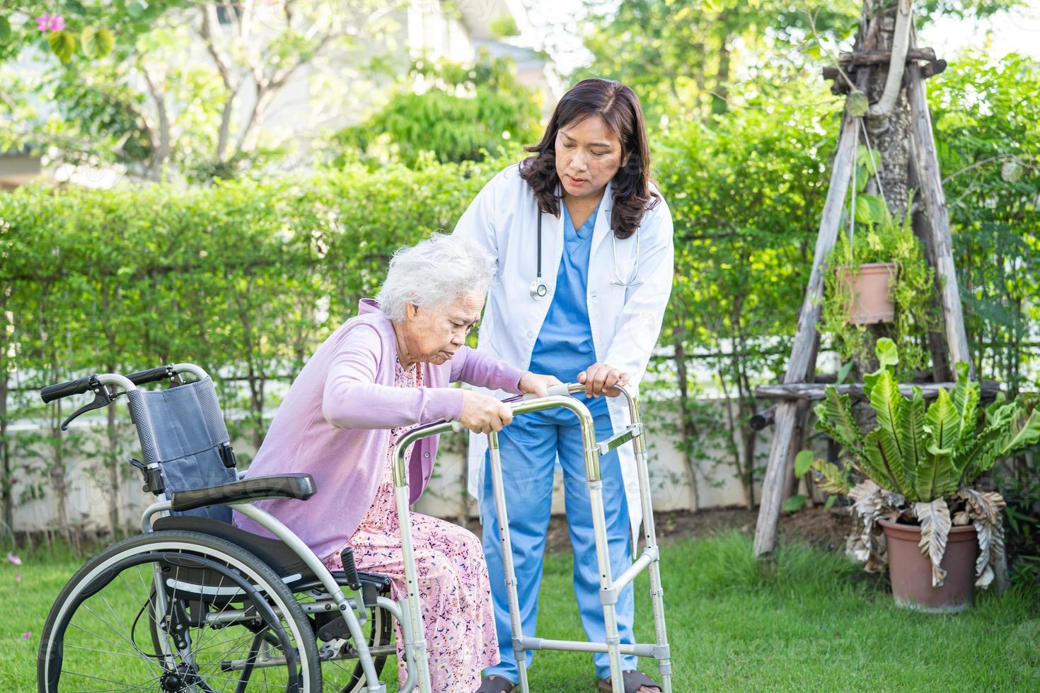 Arzt hilft und pflegt asiatische Senioren oder ältere Frauen, die auf Rollstuhl im Park in der Krankenstation sitzen, gesundes, starkes medizinisches Konzept. foto