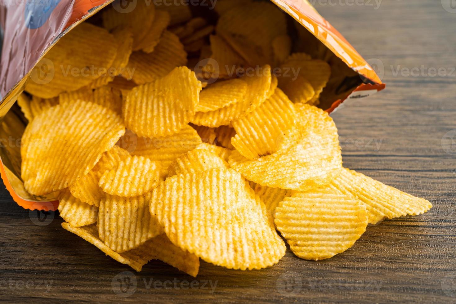 Kartoffelchips, leckeres Grillgewürz würzig für Crips, dünne Scheiben frittierter Snack Fast Food im offenen Beutel. foto