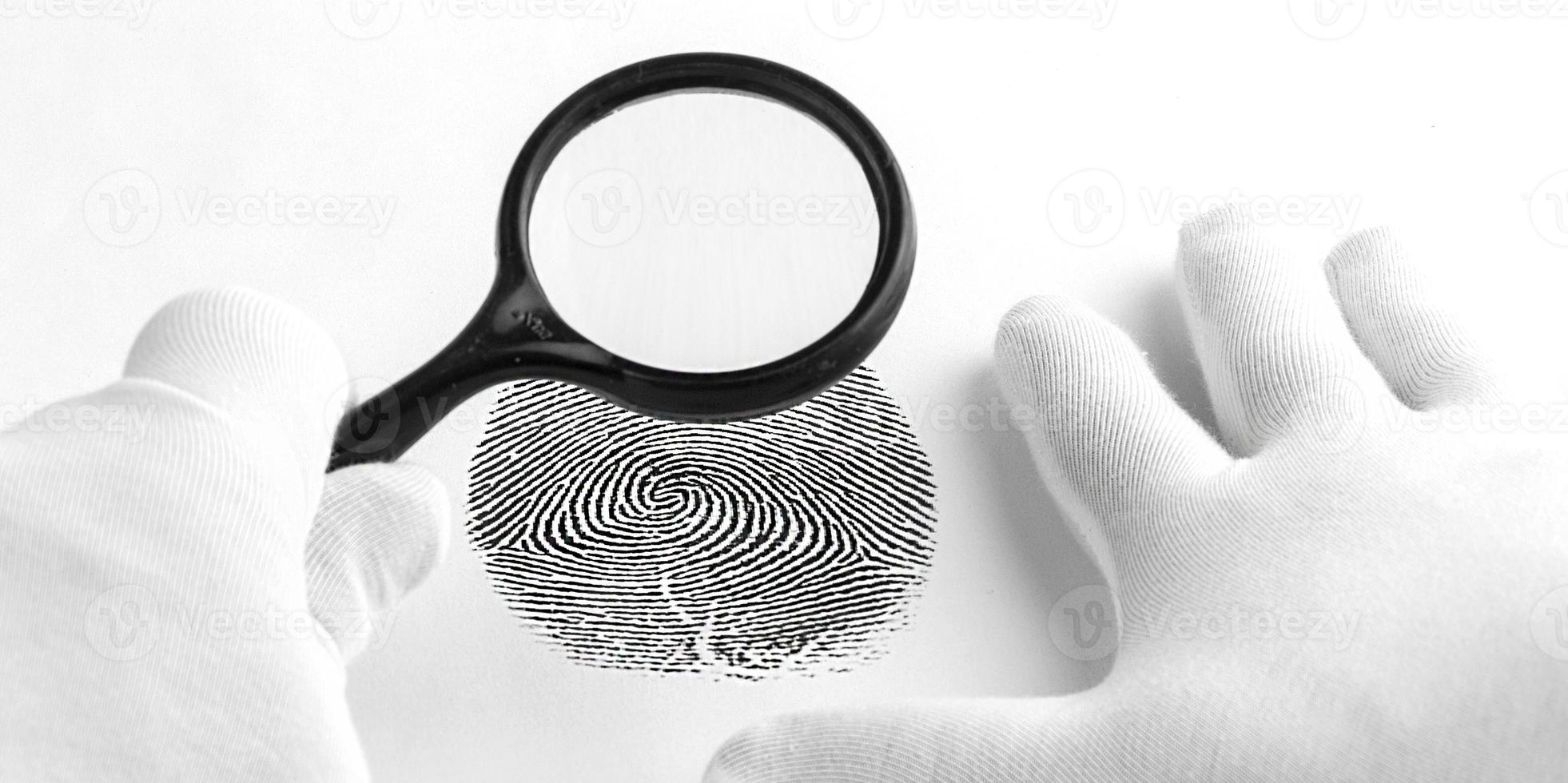 Kriminologieexperte durch eine Lupe, die einen Fingerabdruck betrachtet. foto