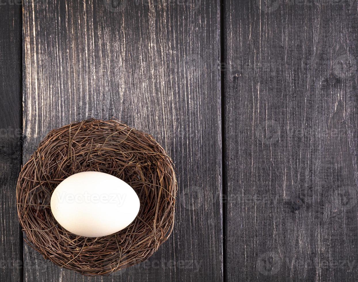das weiße ei auf dem nest auf dem alten hölzernen hintergrund foto
