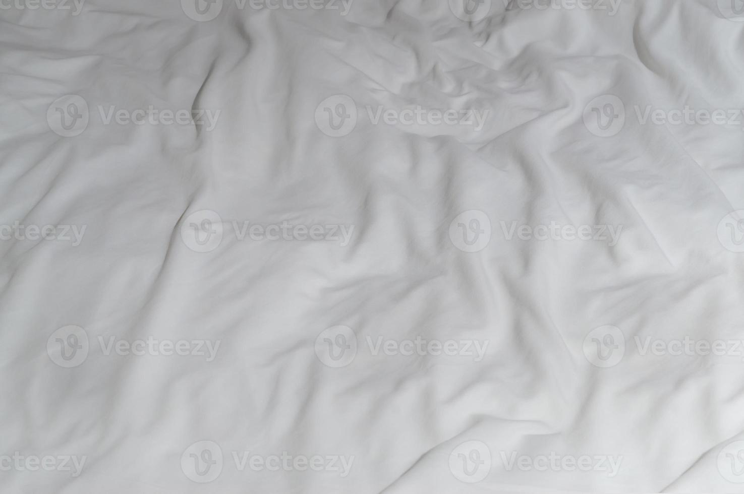 weißes zerknittertes oder zerknittertes Bettlaken oder Decke mit Muster nach dem Gebrauch des Gastes im Hotel, Resortzimmer mit Kopierraum, unordentliche Deckenhintergrundtextur foto