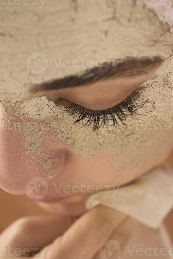 schönheitsverfahren hautpflegekonzept. junge frau, die gesichtsschlamm-lehmmaske auf ihr gesicht aufträgt foto