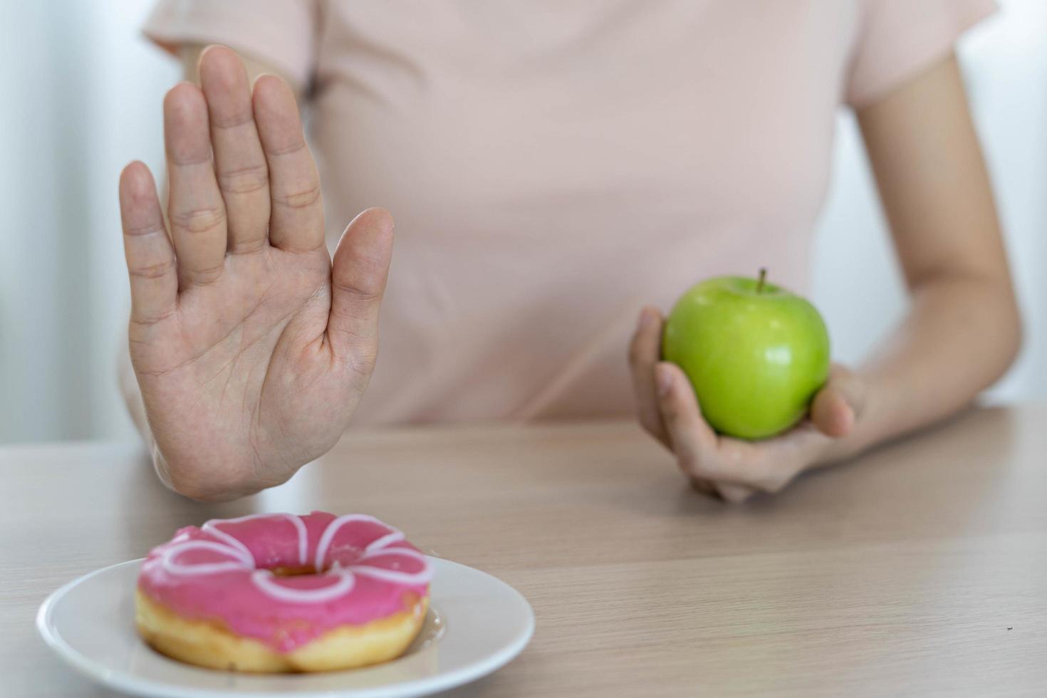 Frauen mit schlankem Körper wählen gesunde Lebensmittel und Junk Food, Frauen wählen grünen Apfel für die Ernährung. gutes gesundes essen. Gewicht verlieren, Gleichgewicht halten, kontrollieren, Fett reduzieren, wenig Kalorien, Routinen, Bewegung. foto