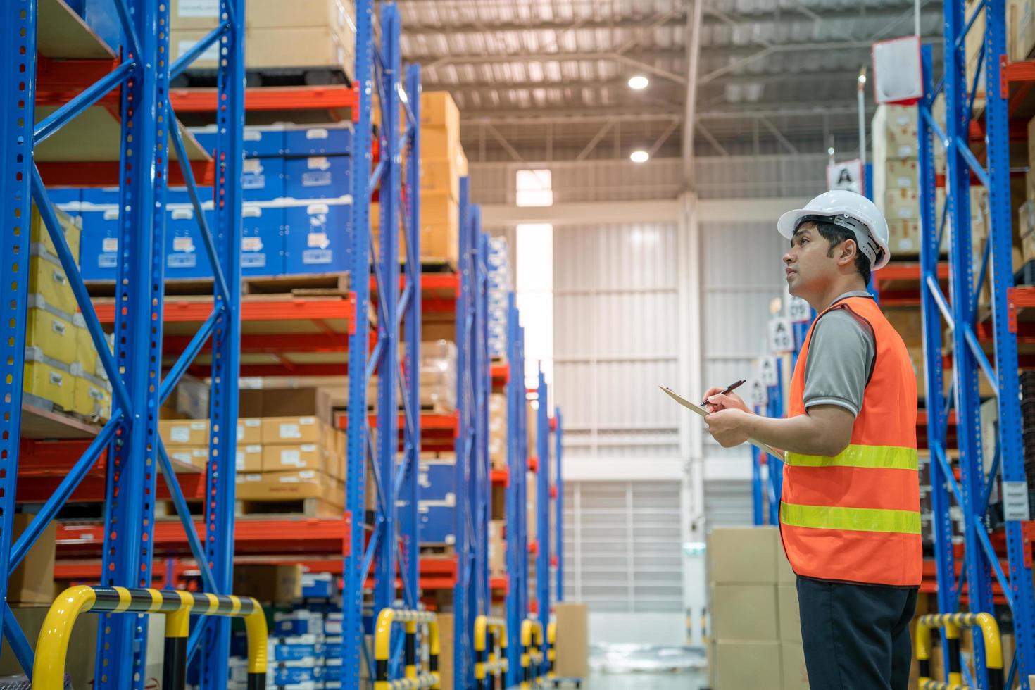 asiatischer männlicher fabrikleiter inspiziert waren im lager oder im bestand und überprüft das lagerprodukt. Transportlogistikgeschäft Versand und Zustellung an Kunden durch eine Spedition. foto