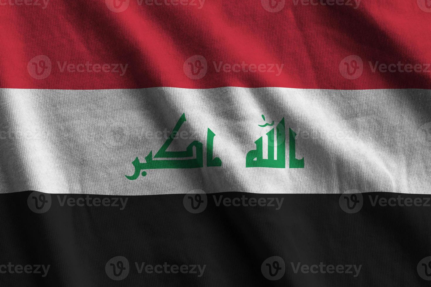 irak-flagge mit großen falten, die unter dem studiolicht im innenbereich wehen. die offiziellen symbole und farben im banner foto