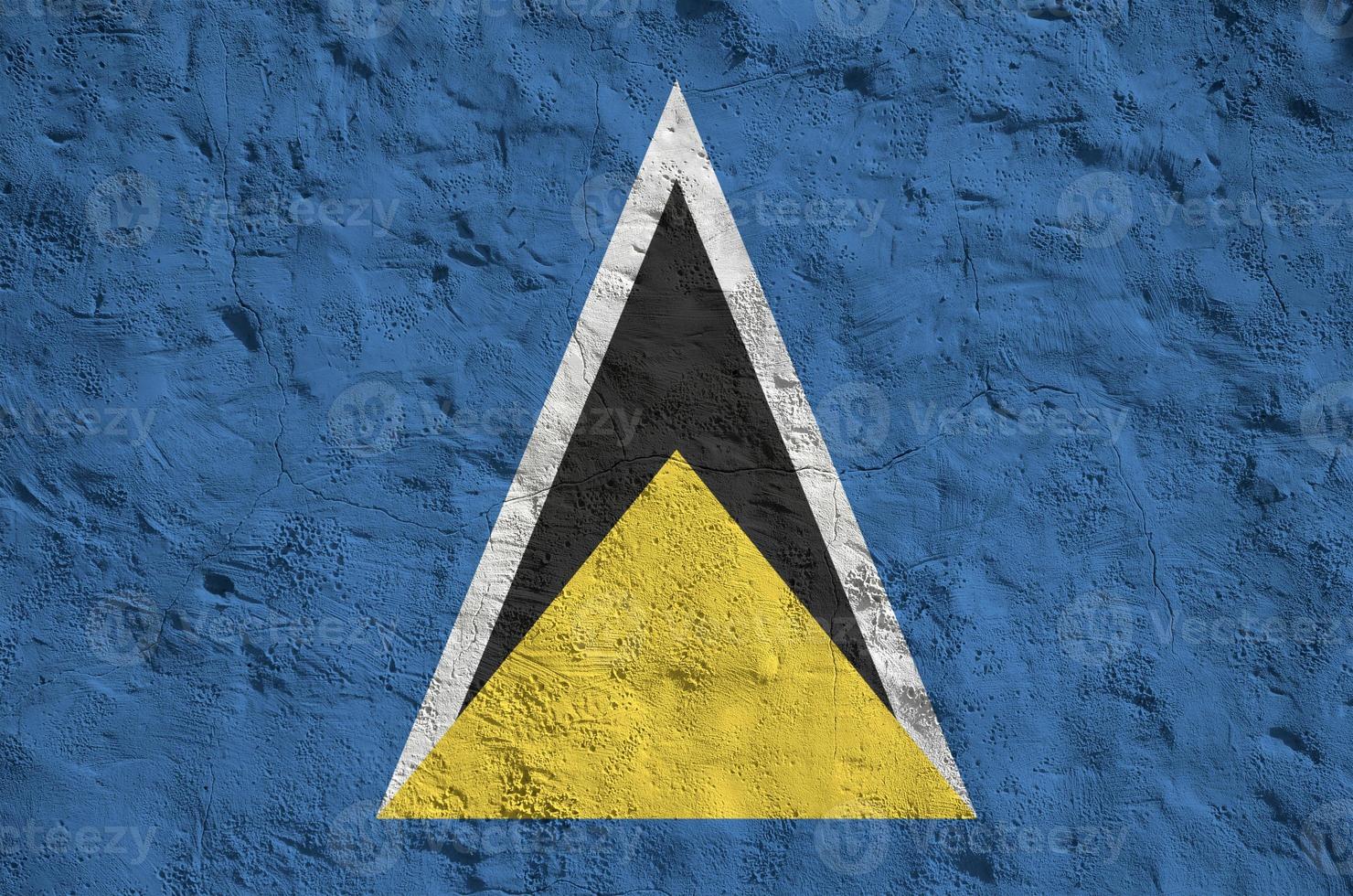 st. lucia-flagge in hellen farben auf alter reliefputzwand dargestellt. strukturierte Fahne auf rauem Hintergrund foto