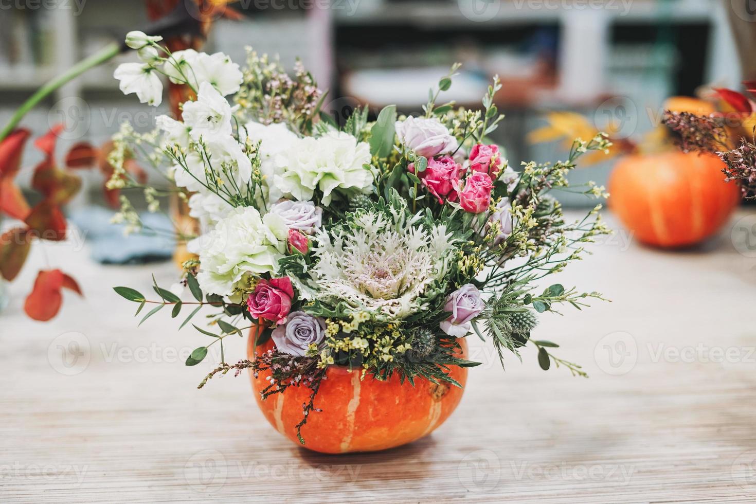 diy herbstblumenarrangement blumenstrauß in kürbis im floristikatelier foto