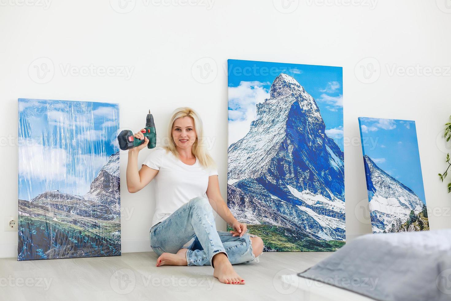 Mädchen hängt zu Hause eine große Fotoleinwand auf foto