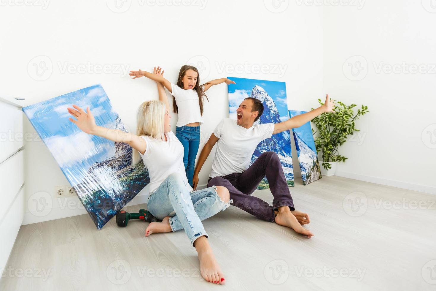 Familie hängt zu Hause eine große Fotoleinwand auf foto