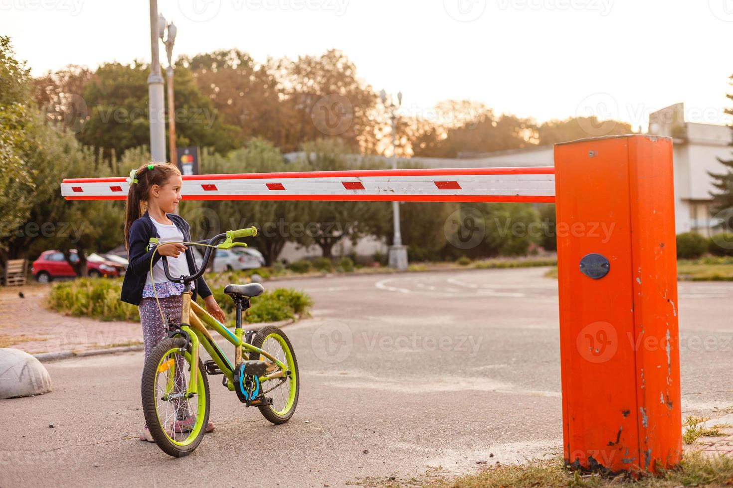 kleines Mädchen auf einem Fahrrad in der Nähe der Schranke foto