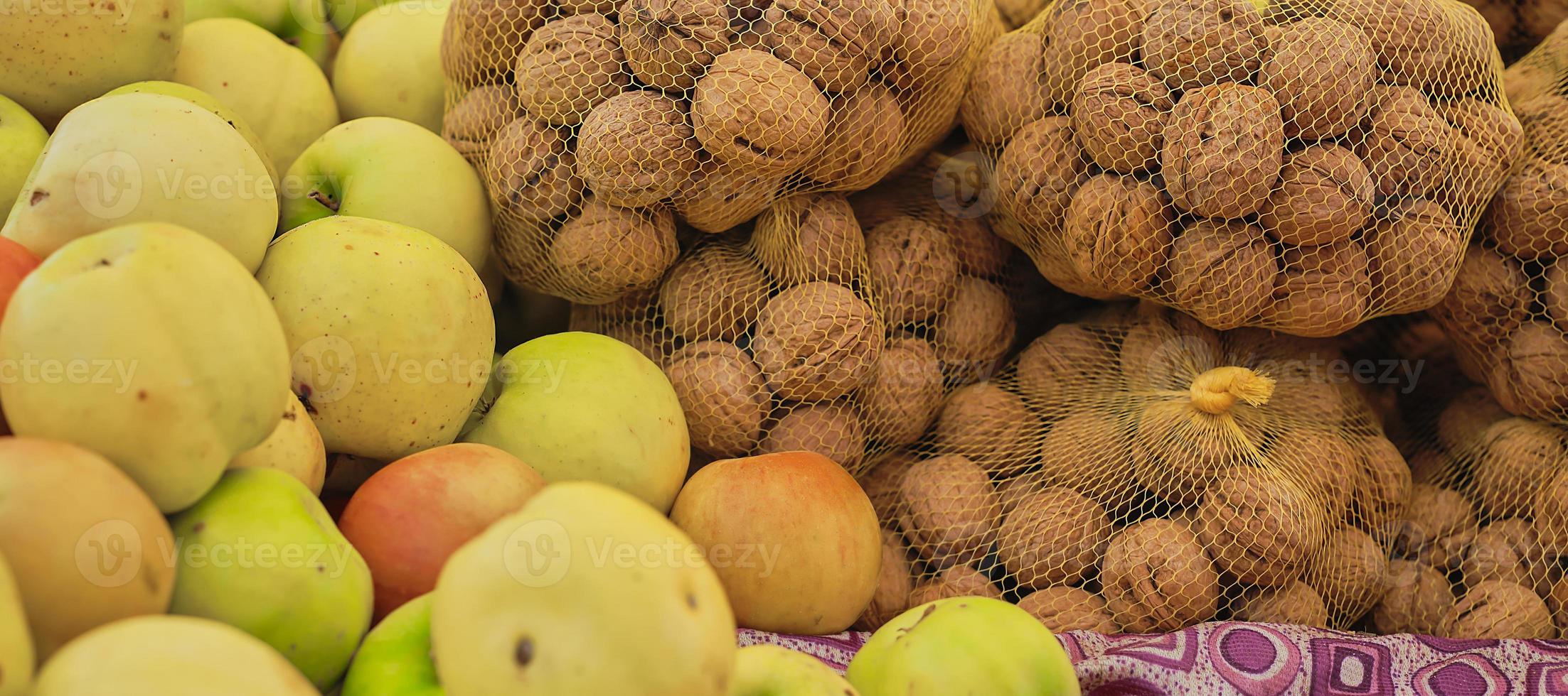 Walnüsse und Äpfel auf der Theke auf dem Bauernmarkt, selektiver Fokus auf reife Produkte, Vitrine in Lebensmitteln foto