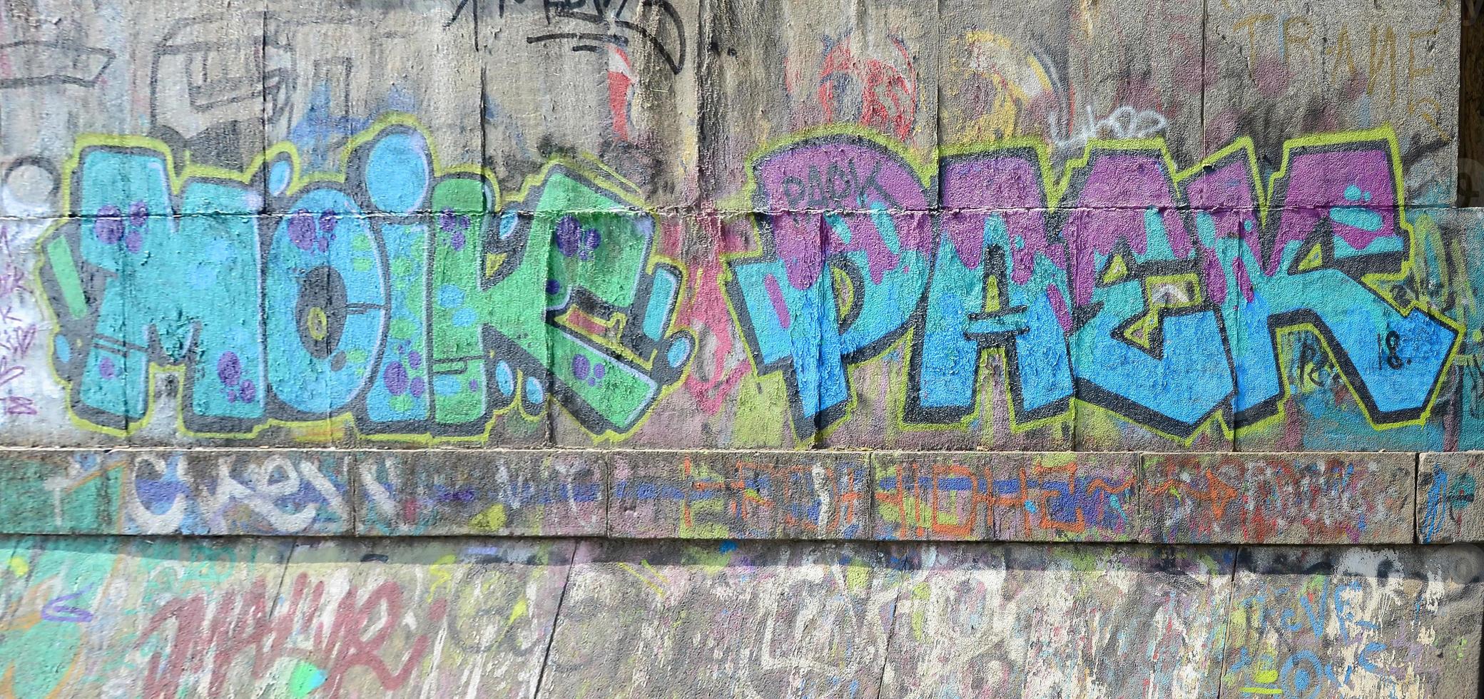 Fragment von Graffiti-Zeichnungen. Die alte Wand ist mit Farbflecken im Stil der Straßenkunstkultur dekoriert. farbige Hintergrundtextur in kalten Tönen foto